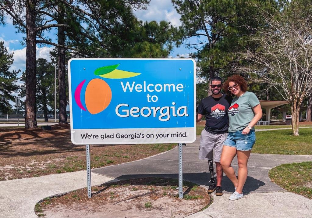 a couple standing next to the welcome to georgia sign