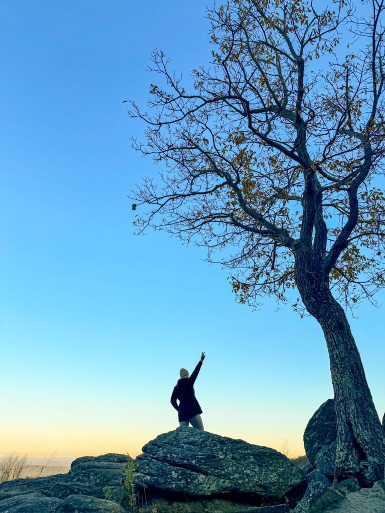 woman standing on a rock mountain experiencing slow travel in the mountains