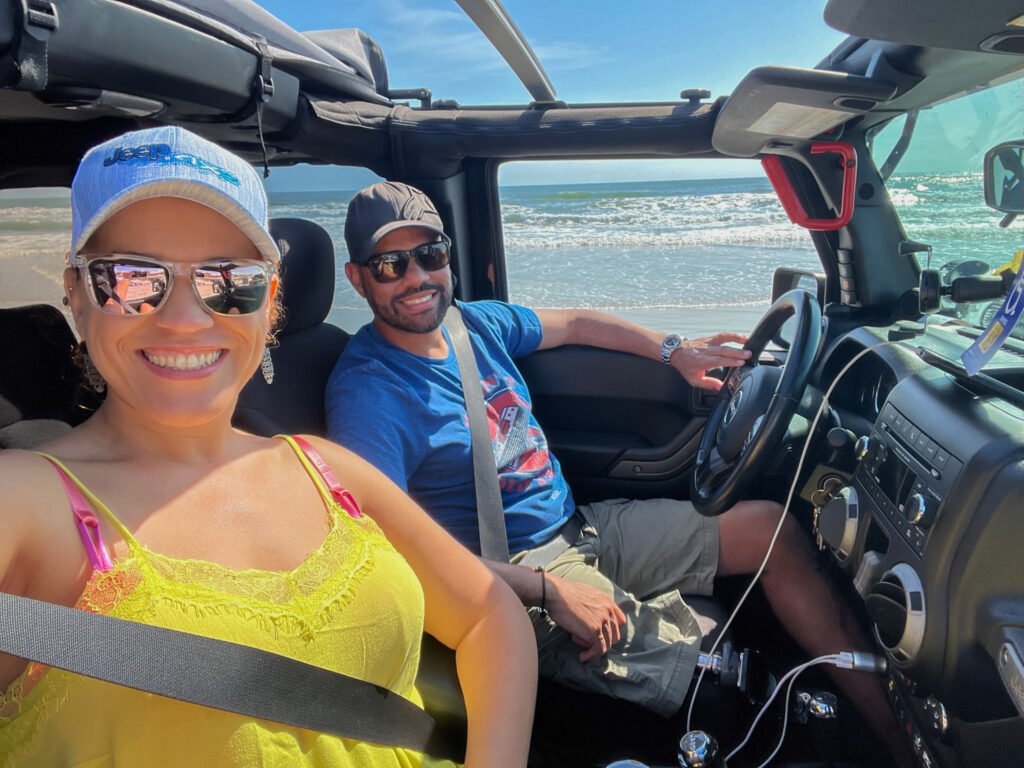 couple inside a Jeep by the beach with the top off