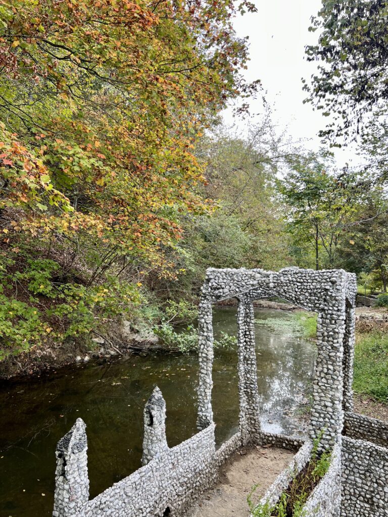 bridge stone sculpture with creek and fall foliage in the background