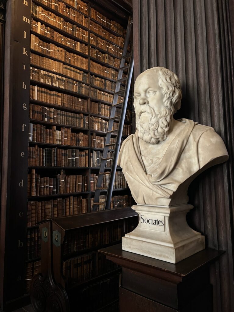 Socrates marble bust and bookshelves with old books inside the Long Room of the Old Library at Trinity College Dublin