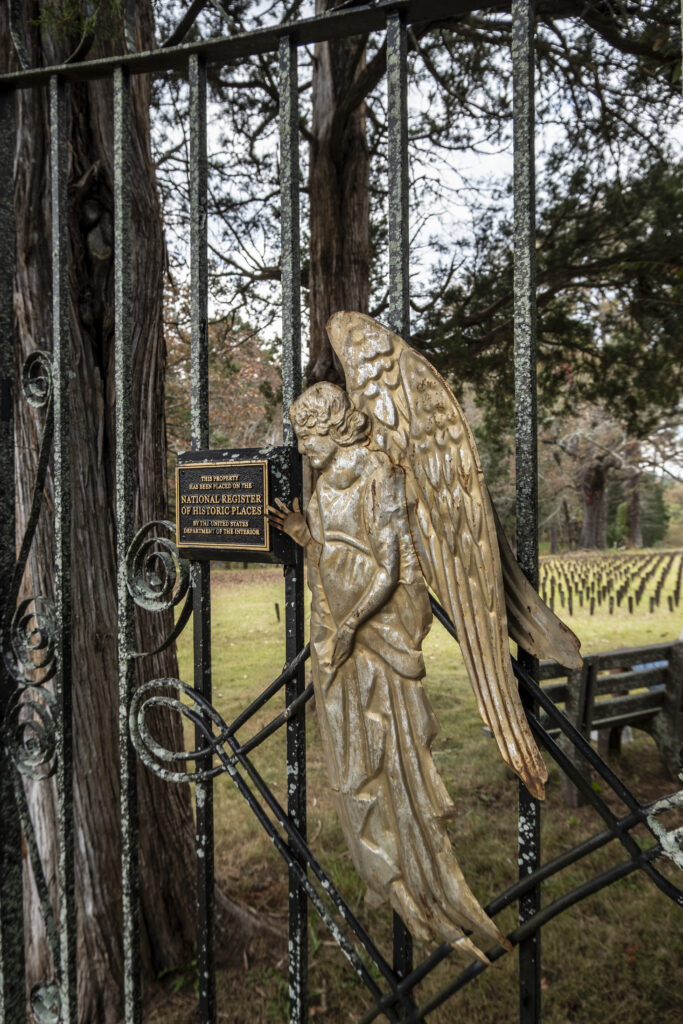 Entrance gate at Cedar Lane Cemetery at Central State Hospital featuring the bronze guardian angel statue and a National Register of Historic Places plaque, marking the site where over 25,000 patients are buried.