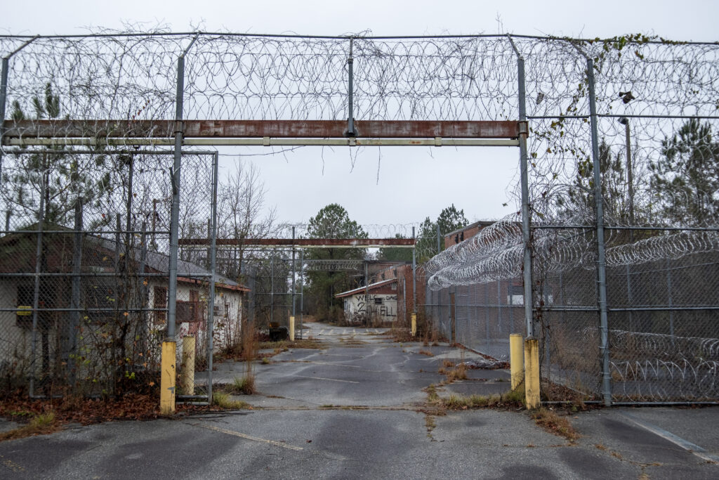 Entrance to Scott State Prison in the Holly Building at Central State Hospital, with barbed wire and visible decay, one of several hospital buildings later converted into a prison facility.