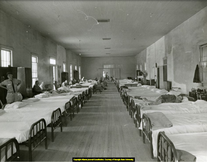 Historic black and white photograph showing rows of beds lined up next to each other inside one of the wards at Central State Hospital, illustrating the overcrowded conditions that defined the institution at its peak.